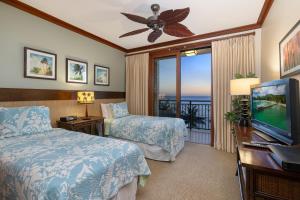 a bedroom with two beds and a television and a balcony at Ko Olina Beach Villas B610 in Kapolei