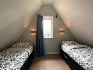 2 camas en un dormitorio ático con ventana en Vakantiewoning Westkaap, en Westkapelle