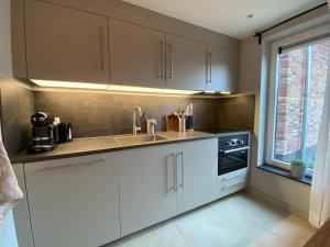 Una cocina con gabinetes blancos y un fregadero y una ventana. en Vakantiewoning Westkaap, en Westkapelle