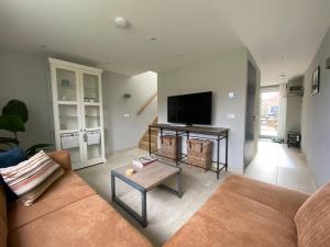 Una sala de estar con un sofá y un televisor. en Vakantiewoning Westkaap, en Westkapelle