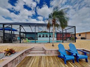 two blue chairs and a palm tree next to a pool at Tortuga Too in Fort Myers Beach