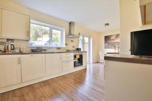 a large kitchen with white cabinets and a large window at Garden Station Dwelling in Rumney in Cardiff