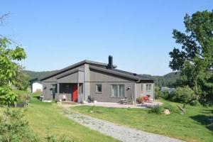 una pequeña casa en un campo con un patio de césped en Underbart hus med fantastisk havsutsikt & nära till bad en Svanesund