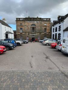 a parking lot with cars parked in front of a building at Charming and Cosy - Black's Land in Inveraray