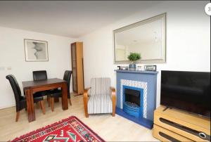 a living room with a fireplace and a table and a television at A Delightful Retreat in Oxford in Oxford