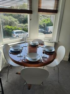 una mesa de madera con sillas, platos y copas de vino en Beautiful 2BR Home close to Beachfront, en Weston-super-Mare