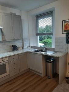 cocina con armarios blancos, fregadero y ventana en Beautiful 2BR Home close to Beachfront, en Weston-super-Mare
