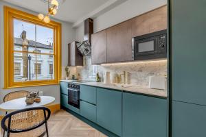 a kitchen with blue cabinets and a table and a window at Hammersmith Residences by MySquare in London