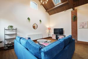 a living room with a blue couch and a tv at Victorian Summer Retreat in Liverpool in Knowsley