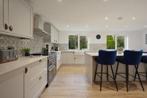 a kitchen with white cabinets and blue bar stools at Victorian Summer Retreat in Liverpool in Knowsley