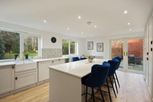 eine Küche mit weißen Schränken und blauen Barhockern in der Unterkunft Modern 5BR Victorian Home in Liverpool in Knowsley