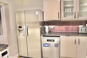 eine Küche mit einem Kühlschrank und Schränken aus Edelstahl in der Unterkunft A peaceful home with a garden in Reading
