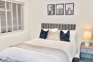 a bedroom with a bed with white sheets and pillows at A peaceful home with a garden in Reading