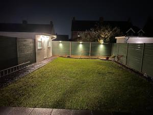 podwórze z ogrodzeniem w nocy z oświetleniem w obiekcie A peaceful home with a garden w mieście Reading