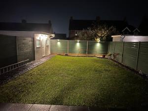 a yard with a fence at night with lights at A peaceful home with a garden in Reading