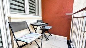 a chair and a table on a balcony with a laptop at Spacious & attractive 600m-7minuta hoda od centra, mogucnost za parking-apartmani-nsmilos in Novi Sad