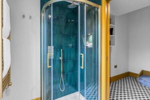 a shower with blue tiled walls and a glass door at Hammersmith Residences by MySquare in London