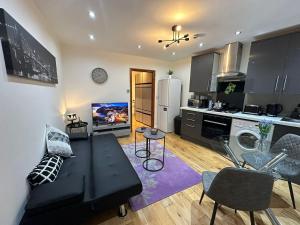 a living room with a black couch and a kitchen at Snug retreat in Reading in Earley