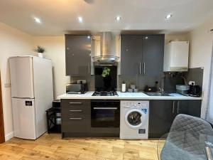 a kitchen with a refrigerator and a washing machine at Snug retreat in Reading in Earley