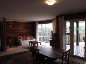 una sala de estar con una mesa y un sofá en Trust Knysna Forest Farm Lodge, en Knysna
