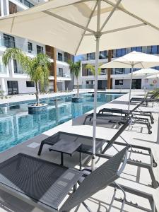 uma piscina com cadeiras e mesas e um guarda-sol em One bedroom apartment, Universal Residences em Pafos