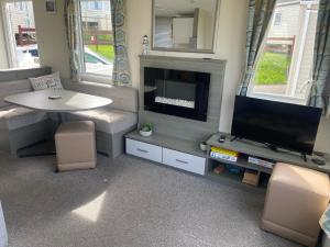sala de estar con TV de pantalla plana y mesa en Littlesea Haven fleetview en Weymouth