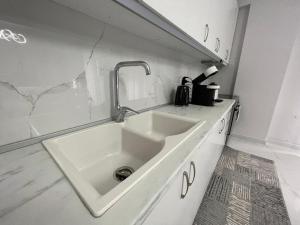 - une cuisine blanche avec évier et comptoir dans l'établissement Luxury Apartment Korca, à Korçë