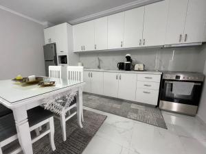- une cuisine avec des placards blancs, une table et une cuisinière dans l'établissement Luxury Apartment Korca, à Korçë