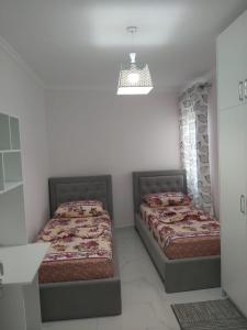 2 bedden in een witte kamer met 2 slaapplaatsen bij Luxury Apartment Korca in Korçë