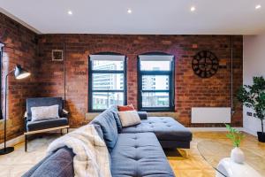 a living room with a blue couch and a brick wall at Luxury Oversized Urban Apartment with Signature Bathroom in Leeds