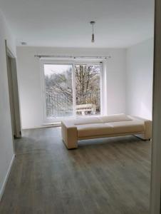 een witte kamer met een bank voor een raam bij 3-Bedroom house with Sea view balcony in Swansea