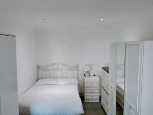 een witte slaapkamer met een bed en een dressoir bij 3-Bedroom house with Sea view balcony in Swansea