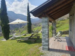 eine Terrasse mit einem Sonnenschirm, einem Tisch und Stühlen in der Unterkunft Agriturismo Nona Rosa in Gravedona