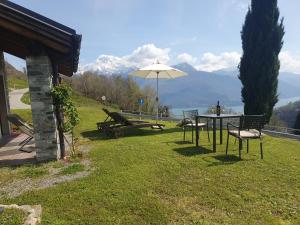 eine Terrasse mit einem Sonnenschirm, einem Tisch und Stühlen in der Unterkunft Agriturismo Nona Rosa in Gravedona