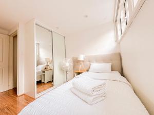 a white bedroom with a bed and a mirror at Ultimo Terrace Homestay in Sydney