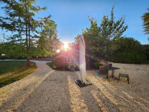 une planche de surf assise sur une route en gravier à côté d'une table dans l'établissement Maison de maître - Les Marizys, à Vouziers