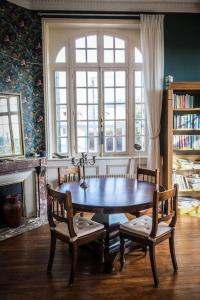ein Esszimmer mit einem Tisch, Stühlen und einem Fenster in der Unterkunft Maison de maître - Les Marizys in Vouziers