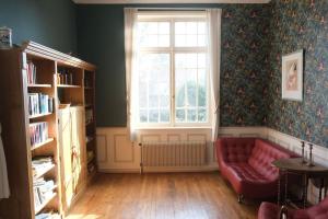 a living room with a red couch and a window at Maison de maître - Les Marizys in Vouziers