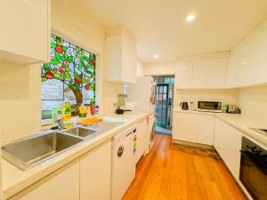 cocina blanca con fregadero y ventana en Ultimo Terrace Homestay en Sídney