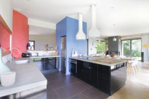 eine Küche mit schwarzen Schränken und einer blauen Wand in der Unterkunft Family villa with swimming pool in Aiguebelette-Le-Lac in Aiguebelette-le-Lac