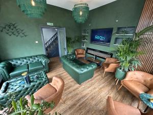 uma sala de estar com um sofá e cadeiras e uma televisão em Hotel Neon em Blackpool