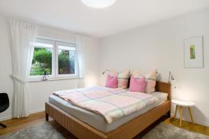 a bedroom with a bed with pink pillows and a window at Ferienwohnung Gut Edel in Müllheim