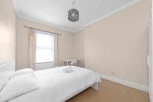 um quarto branco com uma cama e uma janela em Spot Homes Guest House em Londres