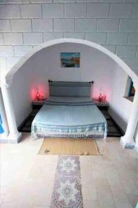 Cette chambre comprend un lit au milieu d'une arche. dans l'établissement Dar Sandra Bizerte, à Bizerte