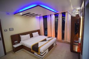 Hotel Asha Inn في Jasidih: غرفة نوم مع سرير مع ضوء أزرق