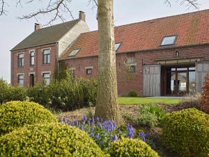 a brick house with a tree in a garden at De neering hoeve vakantiewoning in Wielsbeke