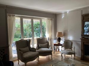een woonkamer met 2 stoelen en een raam bij Elégant appartement sur jardin à Boulogne in Boulogne-Billancourt
