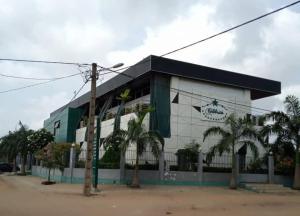 a building with palm trees in front of it at CELEBRITES HOTEL in Ouidah