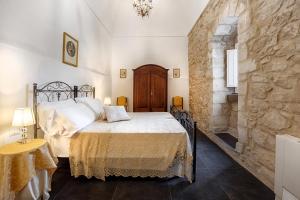 a bedroom with a bed and a stone wall at Ai Due Leoni 1863 in Comiso