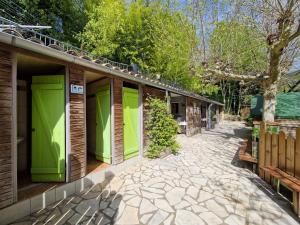 una fila de puertas verdes a un lado de un edificio en Camp des Gorges - Camping Nature en Vallon-Pont-dʼArc